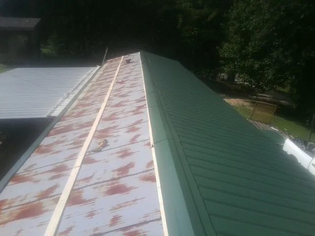 Old rusted panels beside newly installed green metal roofing — Wind Damage Roof Repair by Roofing Brothers in Belleview