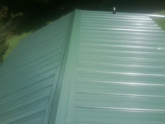 New green metal panels meeting at the ridge of a roof — Flat Roof Repair work by our crew in Belleview