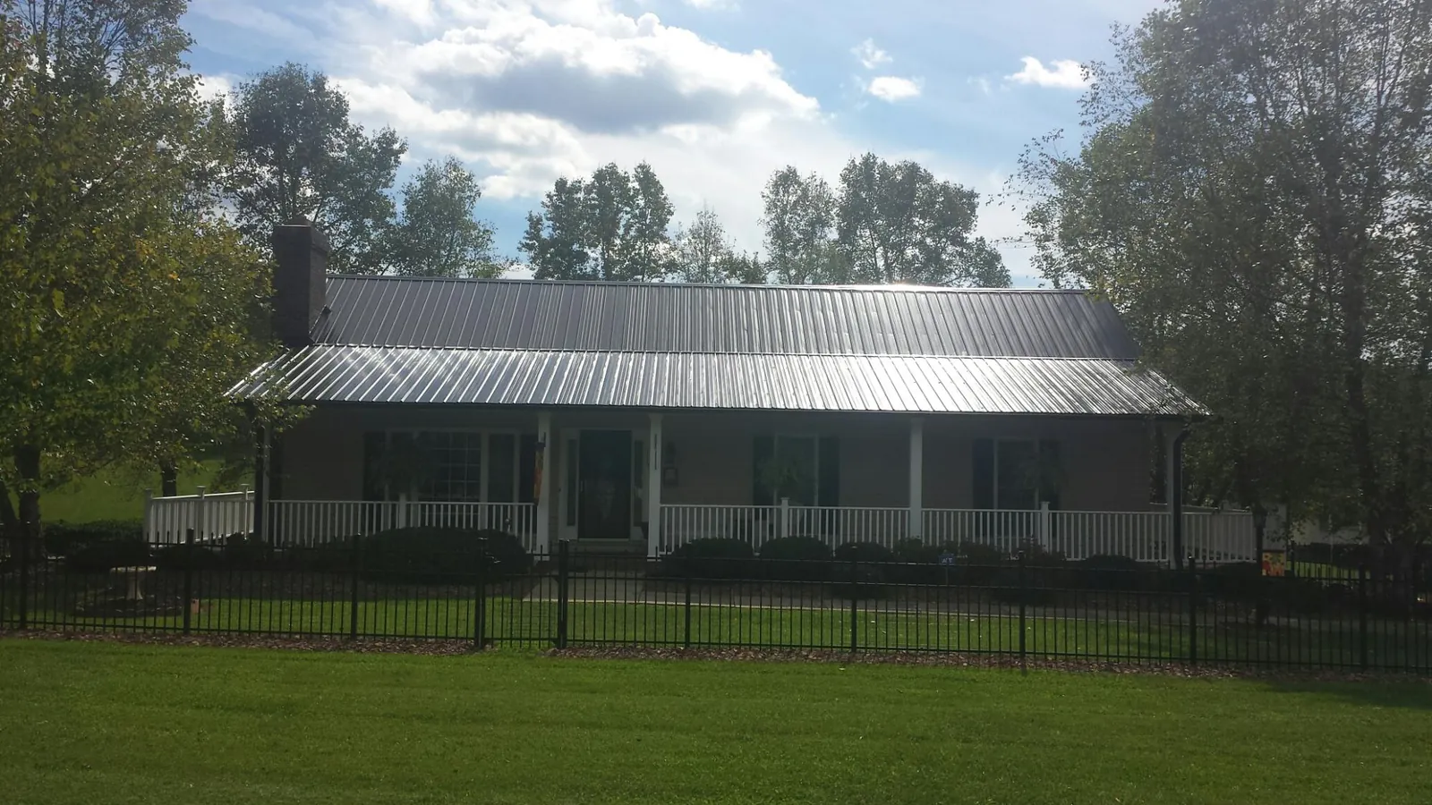 Gray metal roof on a brick ranch with a full width front porch — Gutter Guard Installation work by our crew in Belleview