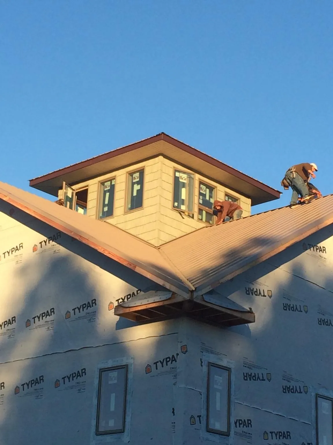 Roofers working around a rooftop cupola on a new metal roof at sunset — Roof Waterproofing in Belleview by Roofing Brothers